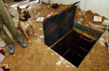 DEIR EL-BALAH, GAZA STRIP - SEPTEMBER 2: In this photo made available by the Israel Defense Force, an Israeli soldier and his dog stand at the entrance to a tunnel September 2, 2004 in the Palestinian town of Deir el-Balah in the Gaza Strip. The army said it uncovered the tunnel, which Palestinians were apparently planning to use to carry out a terror attack in the area, leading to the nearby Jewish settlement of Kfar Darom. (Photo by Tal Naveh/IDF via Getty Images)