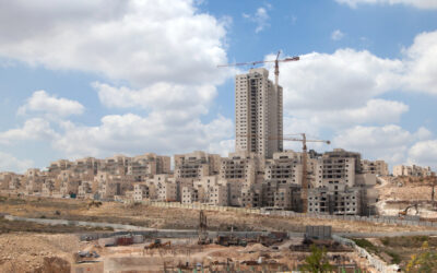 The image shows a construction site with multiple buildings in various stages of completion. There are several cranes positioned around the site, indicating ongoing construction work.