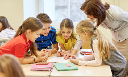group of school kids writing test in classroom