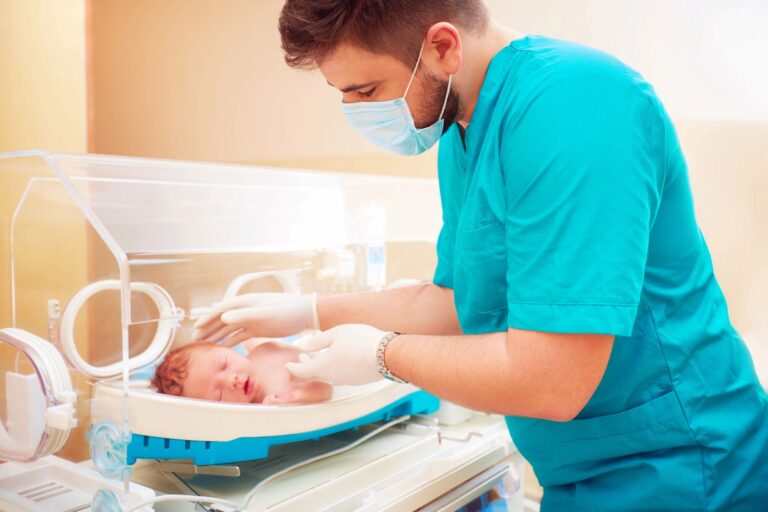 medical staff taking care of newborn baby in infant incubator