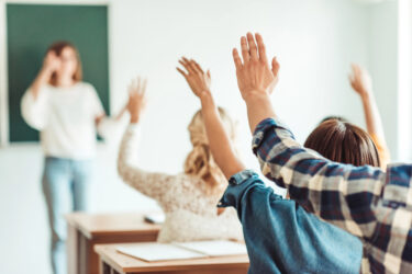 Students raising their hand during a lecture in a classroom